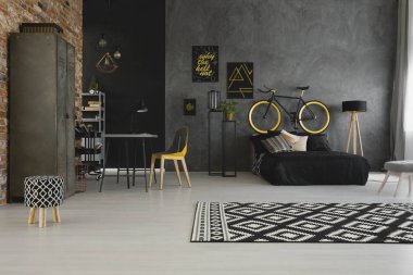 Bir modern, açık boşluk daire iç sarı sandalye bir masa ve bir siyah yatak yatak başı bir bisiklet ile gerçek fotoğraf