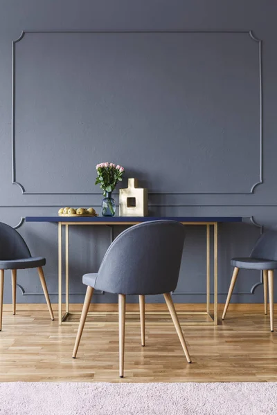 成形と壁と最小限のダイニング ルームのインテリアに木製のテーブルで灰色の椅子 実際の写真 — ストック写真