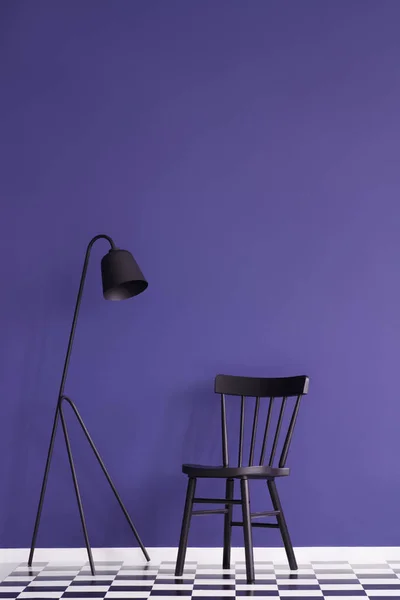 Black lamp and chair set on a violet wall in simple living room interior. Place your product