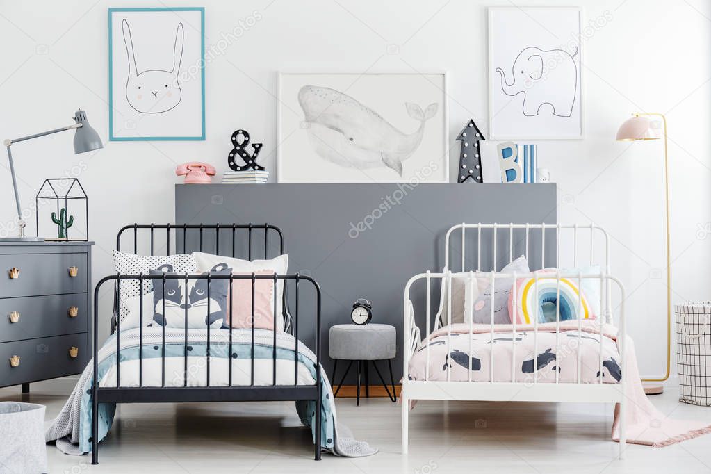 Simple style siblings bedroom interior with black and white beds. Rabbit, whale and elephant posters on white wall and gray drawer cabinet. Real photo