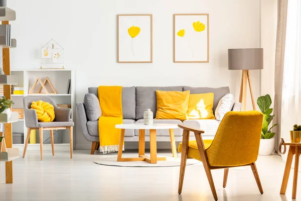 黄色扶手椅在白色客厅内部与海报上面的灰色沙发与枕头 真实照片 — 图库照片