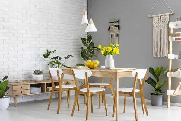 木製のテーブルと黄色い花を持つダイニング ルームのインテリアで椅子の上の白いランプです 実際の写真 — ストック写真