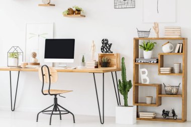 Bir bilgisayar ve bir sandalye ayakta yanında bir işyeri iç süslemeli bir raf ahşap bir masa gerçek fotoğraf