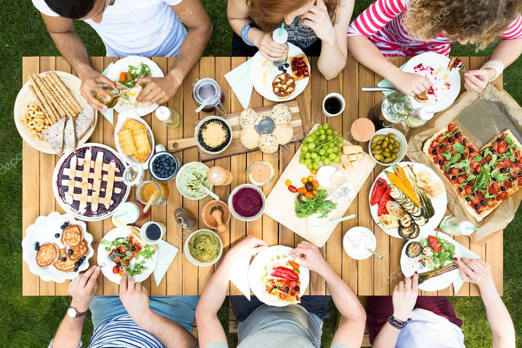 Top view of friends sitting at the table and eating Italian food