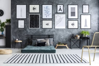 Geniş gri yatak odası iç beton duvara posterler ile yeşil şilte ile altın sandalye