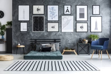 Mavi koltukta geniş daire iç posterler yeşil yatak üzerinde beton duvar ile