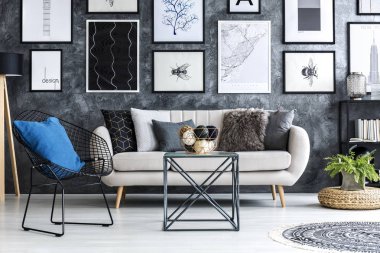 Galeri posterleri ile düz iç bej kanepe yakınındaki mavi yastık ile siyah tekli