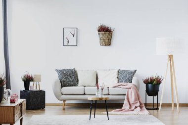 Poster ve sepet heather rahat oturma odası iç kanepe desenli yastıkları ile yanındaki ahşap lambalı beyaz duvar ile