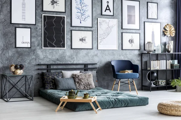 Gri yatak odası iç posterler beton duvar ile yeşil şilte yanındaki mavi koltuk