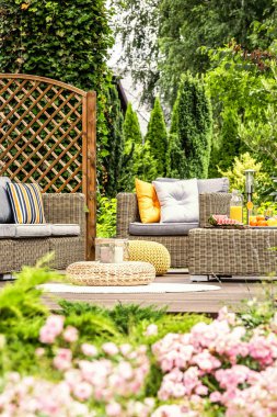 Yastıklar rattan koltuk ile kabarık bahçedeki ahşap veranda üzerinde. Gerçek fotoğraf