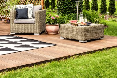 Çiçekler rattan koltuk ve masa meyve desenli halı ile verandada ile arasında. Gerçek fotoğraf