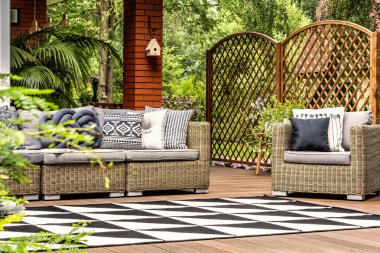 Geometrik halı yastık ile bahçe mobilyaları ile ahşap verandada. Gerçek fotoğraf