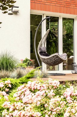 Arka planda bir teras üzerinde tek bir salıncak pembe çiçeklerle Close-up