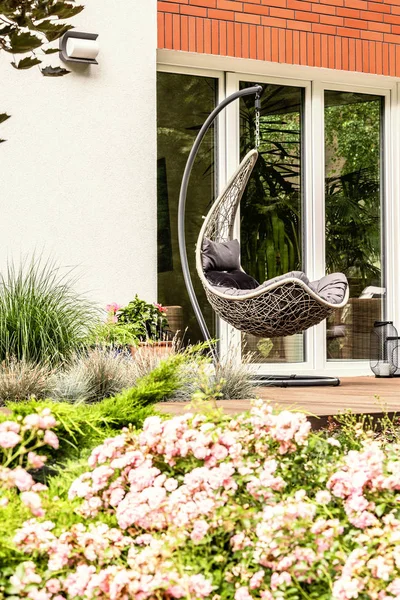 Arka planda bir teras üzerinde tek bir salıncak pembe çiçeklerle Close-up