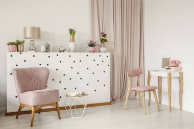 Şık koltuk ve bir polka dot duvar, tahta vanity tablo ve perdeler beyaz yatak odası iç kirli pembe elemanları ile açık bir kitap
