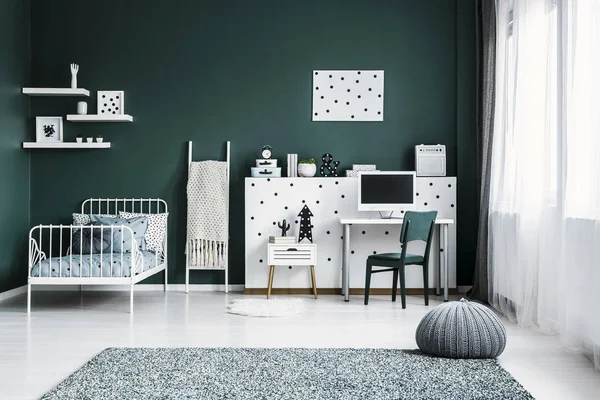 一个深绿色卧室的前景色与床 计算机 墙壁装饰和灰色脚凳在地毯上 — 图库照片