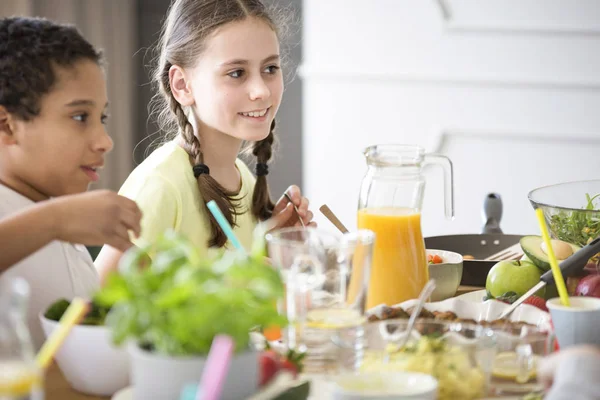 女の子とテーブルによって少年の健康的な自家製食品の完全な絞りたてのオレンジ ジュースを友人の家でこどもの日を祝う — ストック写真