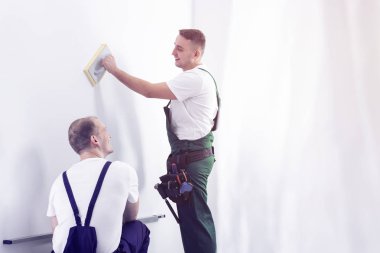 İşçiler üniformalı bir ev tadilatı sırasında konuşuyor. Senin grafik boş bir duvara yerleştirmek