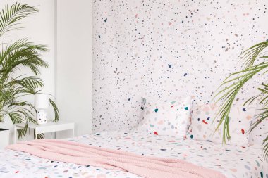 Pembe battaniye ile bitkiler parlak yatak odası iç yastıklar ile desenli yatakta. Gerçek fotoğraf