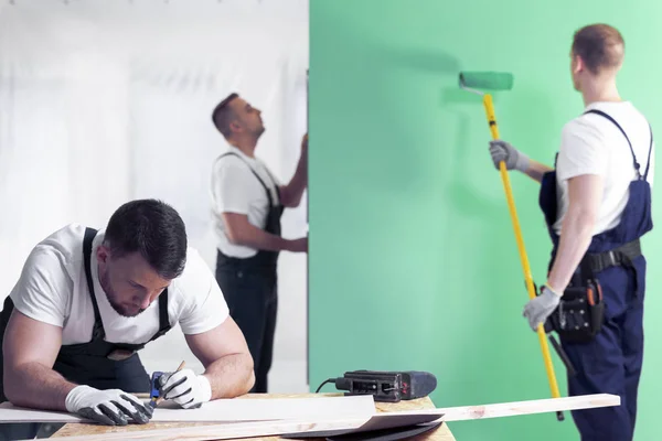 Equipo Renovación Trabajando Una Habitación Dos Trabajadores Pintando Uno Midiendo — Foto de Stock