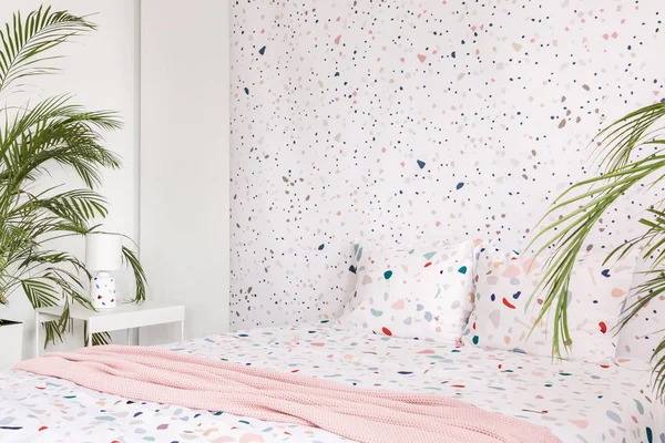 Pembe battaniye ile bitkiler parlak yatak odası iç yastıklar ile desenli yatakta. Gerçek fotoğraf