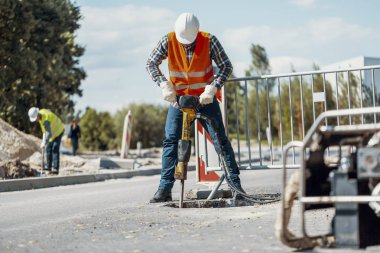Yansıtıcı yelek sokak roadworks sırasında tamiri matkap ile işçi