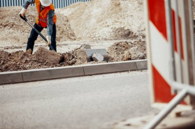 Yolun bir delik kazma bir inşaat işçisi düşük açılı