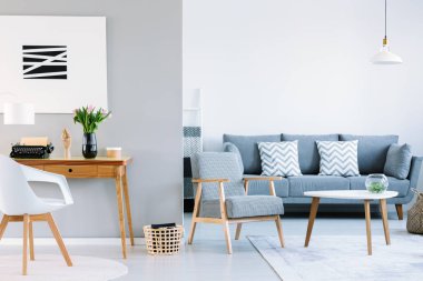 Çalışma alanı ile bir oturma odası iç gerçek fotoğraf. Daktilo ahşap masanın yanındaki iki beyaz minderler ve houndstooth desen tekli kanepe