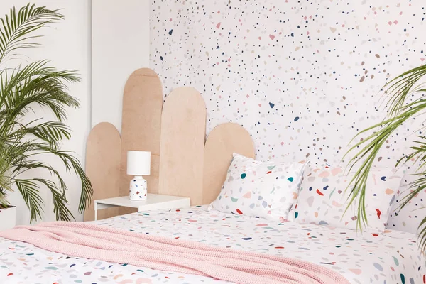 植物の壁紙と明るい寝室のインテリアでパターン化されたベッドの上ピンクの毛布 実際の写真 — ストック写真