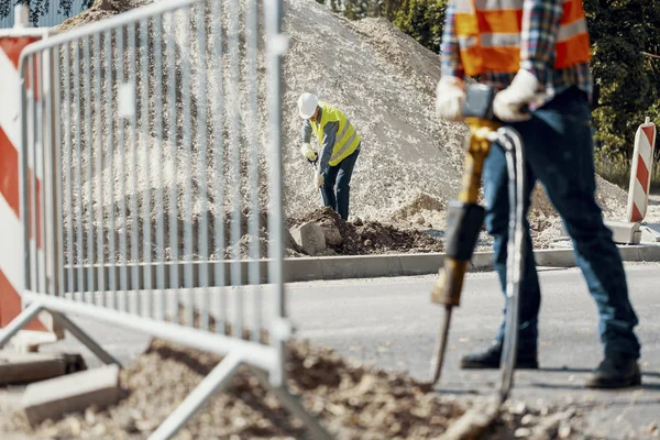 İşçi sokakta roadworks sırasında çalışma kürek ile yelek ve kask