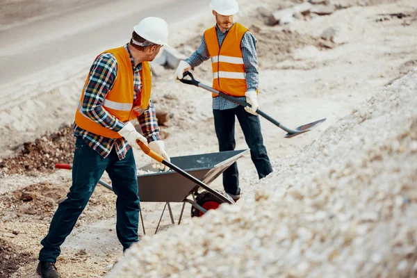 Homens Uniforme Com Pás Colocando Areia Carrinho Mão Durante Trabalho — Fotografia de Stock