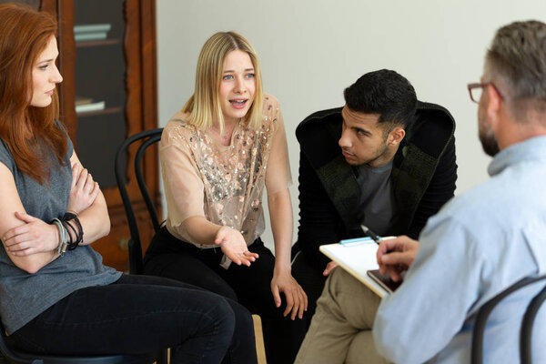 Young woman talking to her therapist during meeting of support group