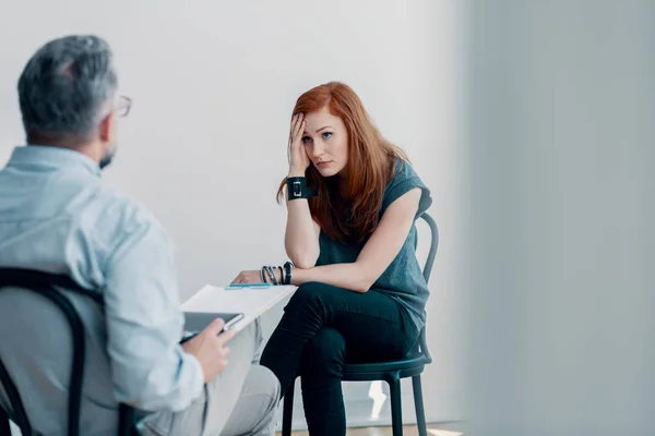 一个害怕的年轻女人在一个聪明的办公室里跟心理医生谈虐待 — 图库照片