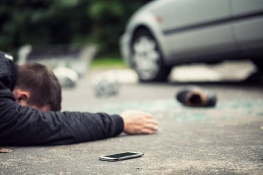 Telefonunu yanındaki sokakta yatan ölü trafiğe kapalı. Ayakkabı, kırık cam ve arka planda bulanık araba