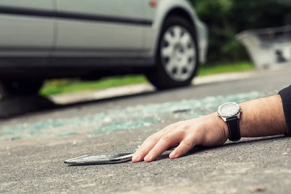 壊れた携帯電話の横にある道路上に横たわって時計の手のクローズ アップ — ストック写真