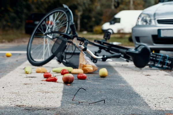 在一辆破自行车旁边的行人过路处散落的蔬菜 — 图库照片
