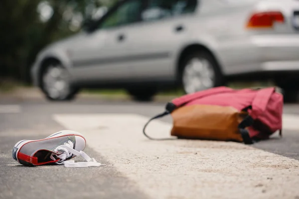 与汽车相撞后行人过路处的儿童鞋和背包特写 — 图库照片