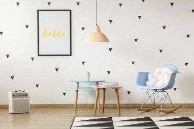 Bir düğüm ile mavi bir sallanan sandalye yanında iki pastel renk tablo ile bir geniş oyun odası iç gerçek fotoğraf minder ayakta üçgenler duvar kağıdı ile duvara