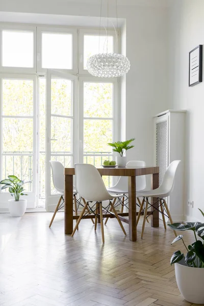 バルコニー付けの明るいダイニング ルーム インテリアのランプの下でテーブルに白い椅子 実際の写真 — ストック写真