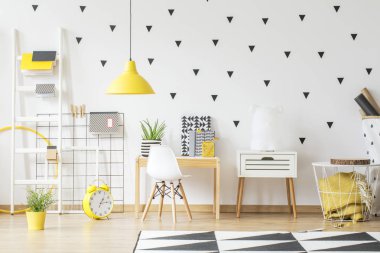 Geometrik çocuğun odası iç ahşap masada beyaz sandalye yanında sarı saat. Gerçek fotoğraf