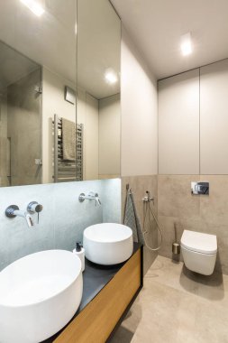 Bej banyo iç ışık ve tuvalet ile beyaz lavabolar yukarıda ayna. Gerçek fotoğraf