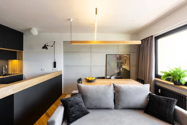 时尚的黑色和灰色的开放空间生活和饭厅内部与一个时髦的沙发和混凝土墙 — 图库照片