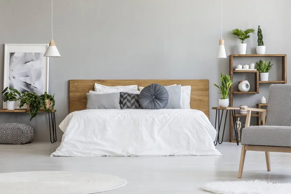 Desenli koltuk gri yatak odası iç bitkiler yatağın yanındaki masada posteri ile. Gerçek fotoğraf