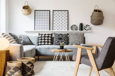 Gri ahşap tekli SCANDI oturma odası iç kanepe yukarıda desenli posterler ile. Gerçek fotoğraf