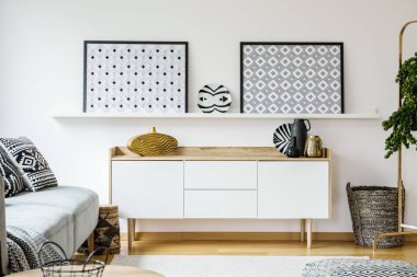 Bir kanepe ve oturma odası iç posterler ile raf bir sepet arasında bir dolapta duran gerçek fotoğraf