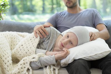 Depressed girl with cancer lying on her boyfriend's lap clipart