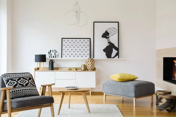 キャビネットの上のポスターとリビング ルームのインテリアの木製肘掛け椅子グレーでパターン化された枕 実際の写真 — ストック写真