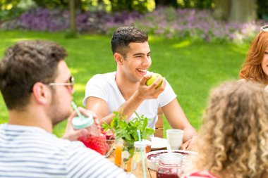 Mutlu İspanyol man veranda üzerinde arkadaşlarıyla bir toplantı sırasında bir elma yemek