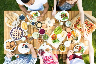 Pasta, pizza ve meyve Bahçe partisi sırasında ahşap masa üzerinde üstten görünüm