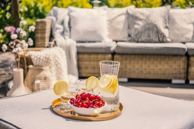 Meyve ve cam rattan masa kanepe ve çiçeklerle terasta su ile. Gerçek fotoğraf arka plan bulanık ile